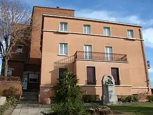 Photographie en couleur d'un jardin, devant un bâtiment.