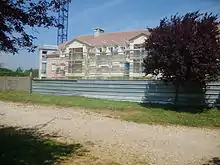 Photographie qui représente la construction d'un bâtiment avec un arbre sur le fond.