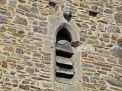 Corbeau à tête grotesque sur fenêtre en arc bouté face est.