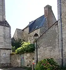 Photographie en couleurs d'un haut bâtiment au toit en ardoises, en arrière plan d'autre construction