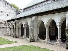 Photographie en couleurs d'une galerie à arcades de pierre couverte d'ardoises.