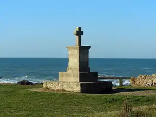 Vue d’une croix en pierre avec la mer en arrière-plan.