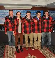 5 personnes dont une femme en veste de ski à carreaux rouges et noirs, pantalon de ville