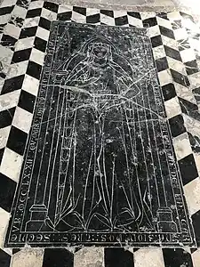 Dalle funéraire noire représentant une femme tenant un livre. Sur le pourtour de la dalle, des écritures en latin sont gravées.