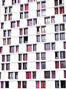 Vue d'une façade d’immeuble blanche avec une disposition géométrique de fenêtres à quatre et deux vantaux.