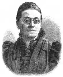 Das Schwarz-Weiß-Foto ist eine Halbfigur-Aufnahme von Hanna Bieber-Böhm, die schräg rechts aus dem Bild blickt. Die Frau in mittleren Jahren hat einen ernsten Gesichtsausdruck und trägt einen Zwicker, von dem eine Kette herunterhängt. Ihr Haar ist hinten dem Kopf zusammengebunden. Sie trägt eine Bluse mit Spitzenkragen, beides in dunklen Farben.