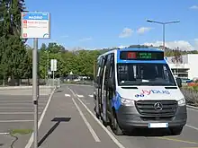 Photographie en couleurs d’un minibus bleu, blanc et noir stationné à un arrêt de bus. Il circule sur la ligne 1, alors la plus fréquentée du réseau.