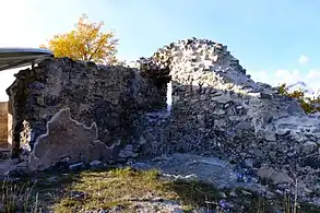Murs formant un angle. Au milieu de celui de droite se trouve une petite ouverture. Sur le mur de gauche, une partie du crépi d'époque subsiste.