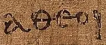 Gros plan sur un mot grec ancien de 5 lettres sur un papyrus.