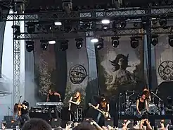 Un groupe entouré de drapeaux joue un concert devant un public