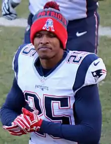 Eric Rowe en maillot blanc des Patriots avec un bonnet et des gants rouge.