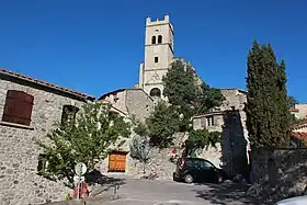 Photo de l'église vue d'en bas, de face, avec son haut clocher quadrangulaire