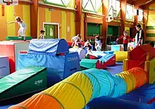 Photo couleur d’un gymnase rempli de matériel de gymnastique multicolore et d’enfants y jouant