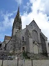 Photographie d'une façade d'église à deux niveaux, avec un portail de style classique surmonté d'une grande fenêtre de style gothique rayonnant