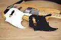 Deux pickguards (l'un blanc, l'autre noir) d'une Jazz Bass Marcus Miller. Ils contiennent une découpe pour laisser passer le micro manche.