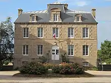 Photographie d'un bâtiment en granit à deux étages, surmontés d'un toit à lucarnes.