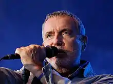 Homme au cheveux gris avec un microphone.