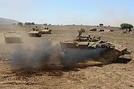 Ce Namer transformé en poste de commandement mobile (à droite) est reconnaissable par le nombre important d'antennes radio montées sur son toit.