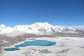 Vue du versant ouest du Gangkhar Puensum depuis le Gophu La, avec à gauche du sommet la longue arête horizontale qui mène à son sommet secondaire, le Liankang Kangri (7 535 m).