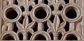 Photographie montrant les ajourages de la partie inférieure d'un panneau en marbre blanc, sculpté et percé, de la paroi du mihrab.