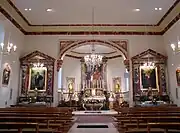 Vue intérieure de la nef vers le chœur et les autels.