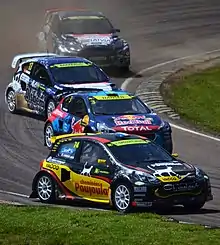 Quatre voitures colorées dérapent pendant un virage.