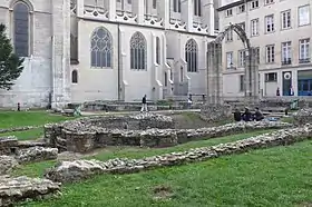 Ruines d'une église situées dans un jardin. En arrière-plan, la façade nord de la cathédrale actuelle.