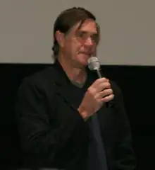 Gus Van Sant explique quelque chose au public à l’aide d'un micro lors d'une avant première à San Francisco.