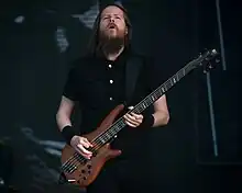 Image d'un homme avec une barbe brune jouant de la basse élèctrique