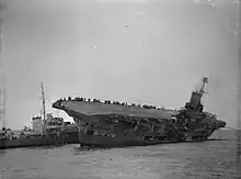Photo en noir et blanc de deux navires côte-à-côte, l'un deux gîtant sur bâbord.