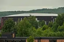 L'amphithéâtre olympique de Hamar derrière des arbres.