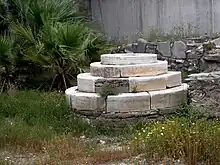 photo couleurs : petite estrade en marbre blanc au milieu d'herbes hautes.