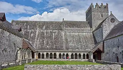 Photographie d'un cloître terminé par une église intacte.