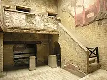 cour intérieure pavée, escalier à droite, balcon à l'étage