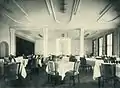 Speisesaal. Links der Durchgang zum Tanzsaal, verborgen durch den vorgezogenen Vorhang.