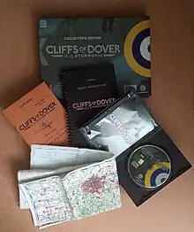 Un coffret sombre avec des boîtes, livrets et cartes sortis devant.