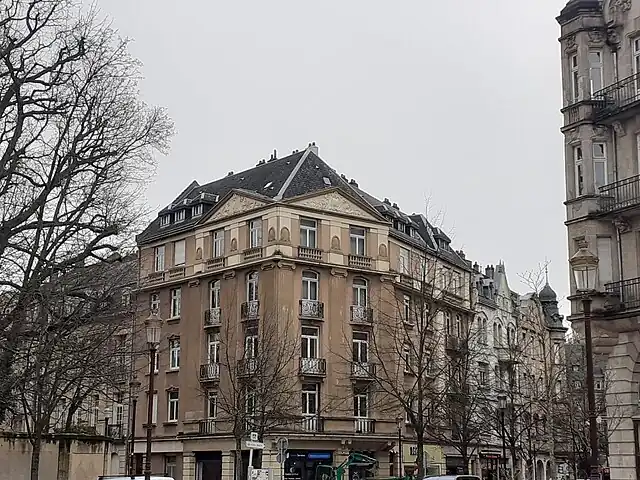 Immeuble de rapport monumental construit par Dirr dans un style néoclassique marquant l'angle de le rue Harelle, point d'entrée depuis la vieille ville française dans la Neustadt allemande.