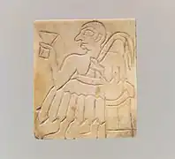 Élément en nacre gravé représentant un homme assis à un banquet.