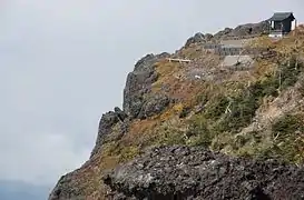 Photo couleur d'un petit sanctuaire en bois au sommet d'une montagne sous une ciel nuageux.