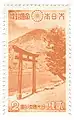 Timbre bicolore orange et blanc montrant une montagne au bord d'un lac, avec au premier plan, un portail traditionnel de sanctuaire shintō.