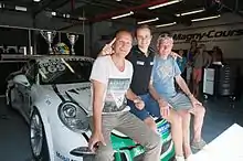 Photographie de trois hommes assis sur le capot d'une voiture