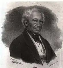 Noir et blanc, en costume 3 pièces, chemise à col cassé et gilet blancs avec veste anthracite, avec nœuds papillon noir. Visage bronzé plutôt allongé, cheveux blancs, yeux bleus, nez aquilin