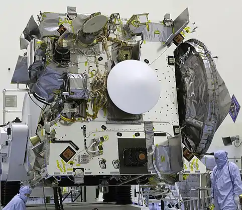 La capsule se trouve sur le « pont » où sont également installés les instruments scientifiques. Le bouclier thermique blanc avant de forme conique est bien visible.