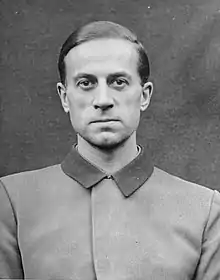 Photo noir et blanc (format photo d’identité, en buste, de face) de Karl Brandt, médecin SS de Hitler. L’homme porte une veste claire au col foncé fermé.