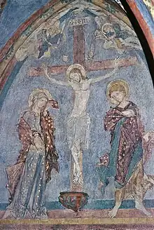 Fresque colorée médiévale représentant une crucifixion avec un homme et une femme de part et d'autre de Jésus crucifié.