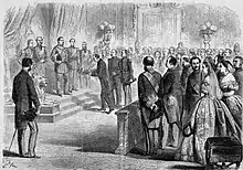 Une foule composée d'hommes en uniformes et de femmes richement parées entoure un petit groupe de personnes dans un palais.