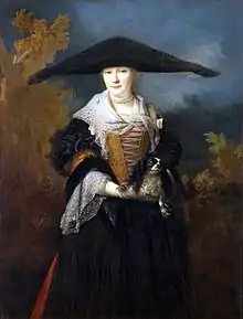 Peinture représentant une jeune femme vêtue d'une robe noire avec un corset jaune, des dentelles blanches et un large chapeau noir triangulaire, et tenant un petit chien entre ses mains.
