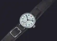 Photographie d'une montre à bracelet noir et cadran blanc