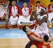 Un joueur américain inscrivant un panier face à un joueur chinois.