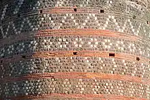 Détail d'un mur avec alternance de rangs de briques et de moellons de pierre de diverses couleurs composant différents motifs décoratifs